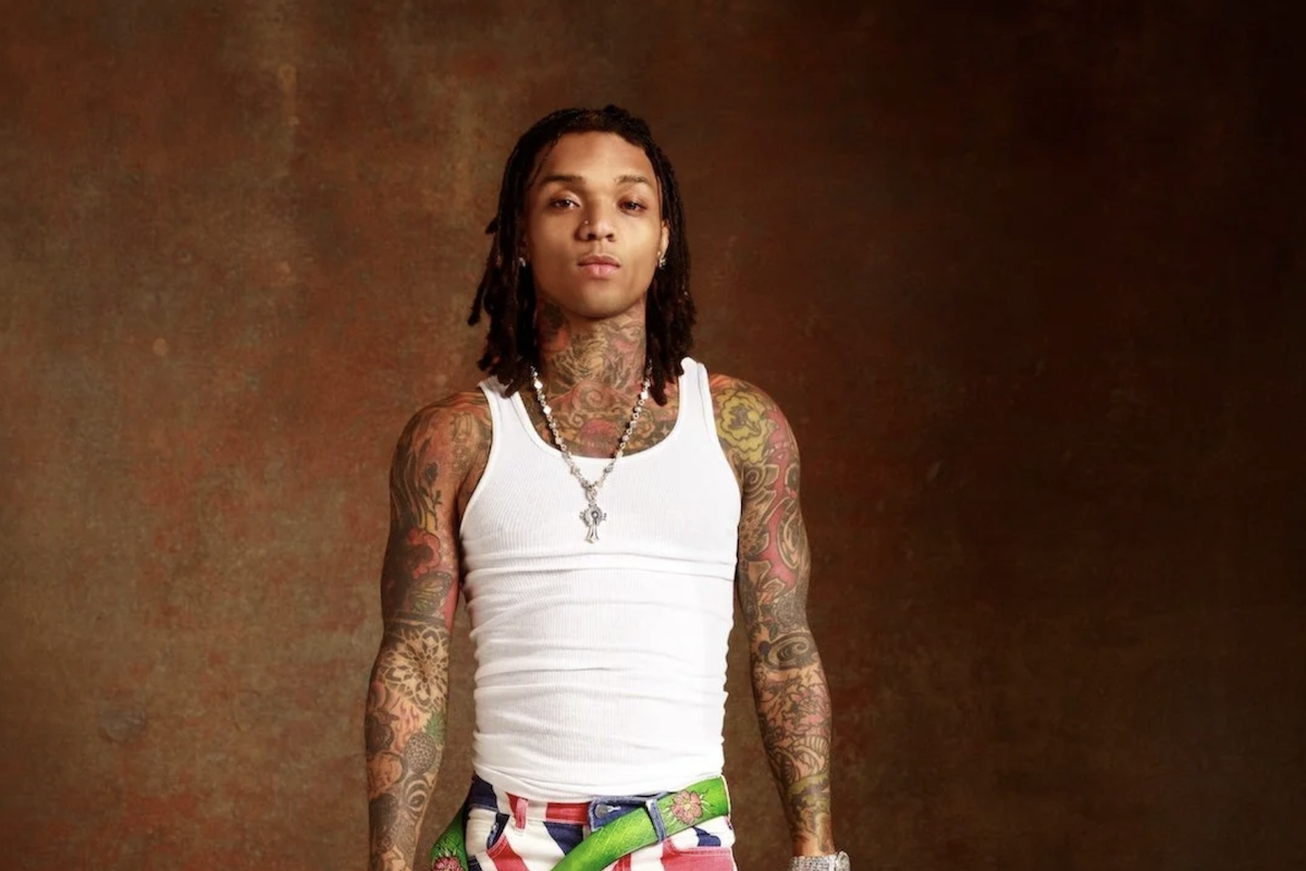 American rapper and singer Swae Lee posing in a white tank top with visible tattoos.